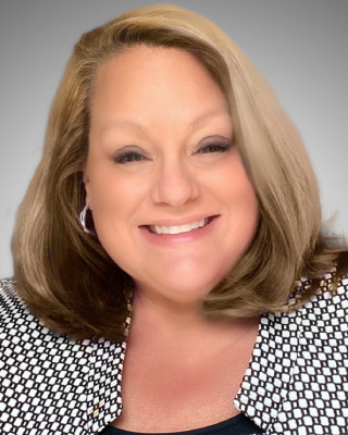 Smiling woman with shoulder-length hair wearing a polka dot top.