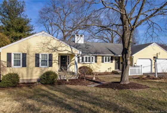 Yellow house with trees and garage.