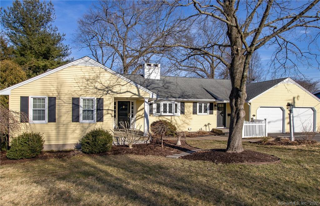 Yellow house with trees and garage.