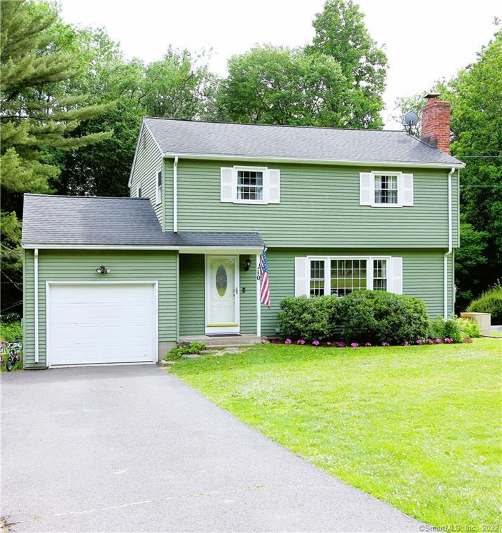 Green two-story house with garage and flag.