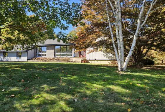 House surrounded by trees and grassy lawn.