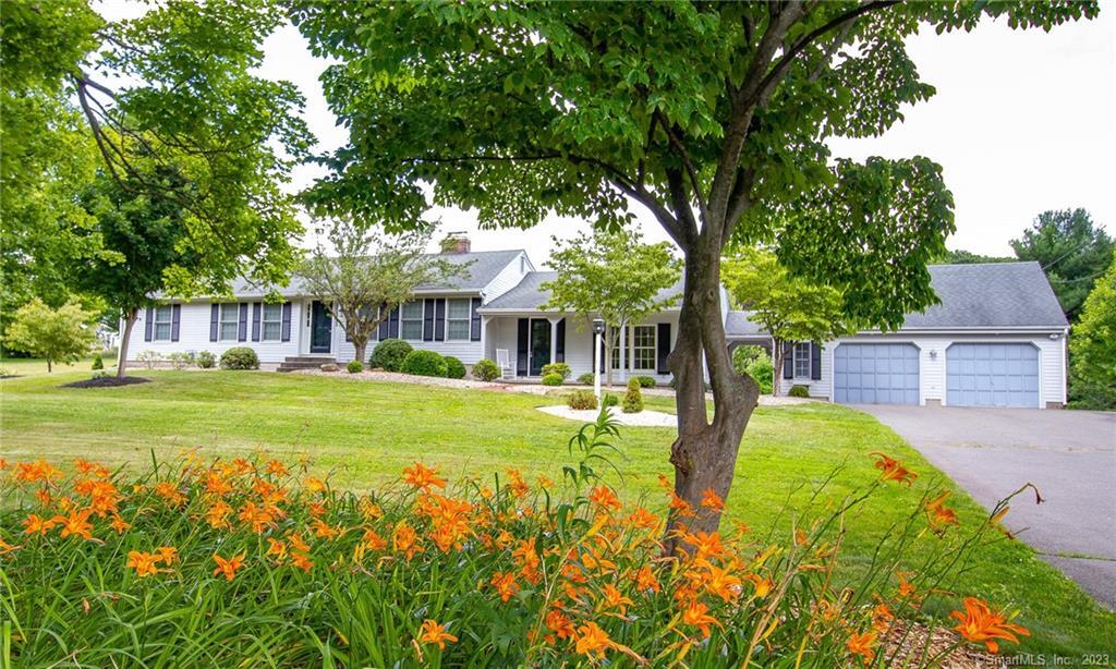 A cozy house with a green lawn and vibrant orange flowers in the foreground.