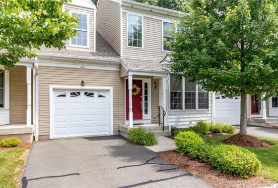 A charming suburban house with beige siding and a red front door.