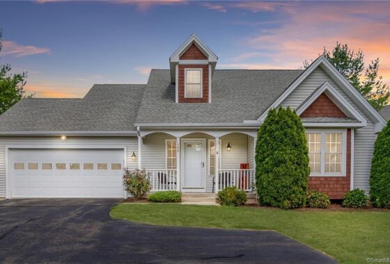Cozy suburban house with a welcoming porch and well-kept lawn at sunset.
