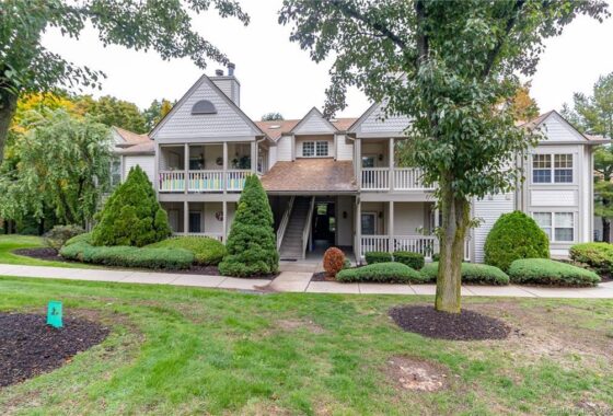 Large traditional house with a welcoming front porch and lush greenery.