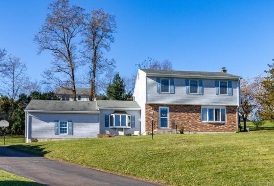 Two-story suburban house with brick and white siding under a clear sky.