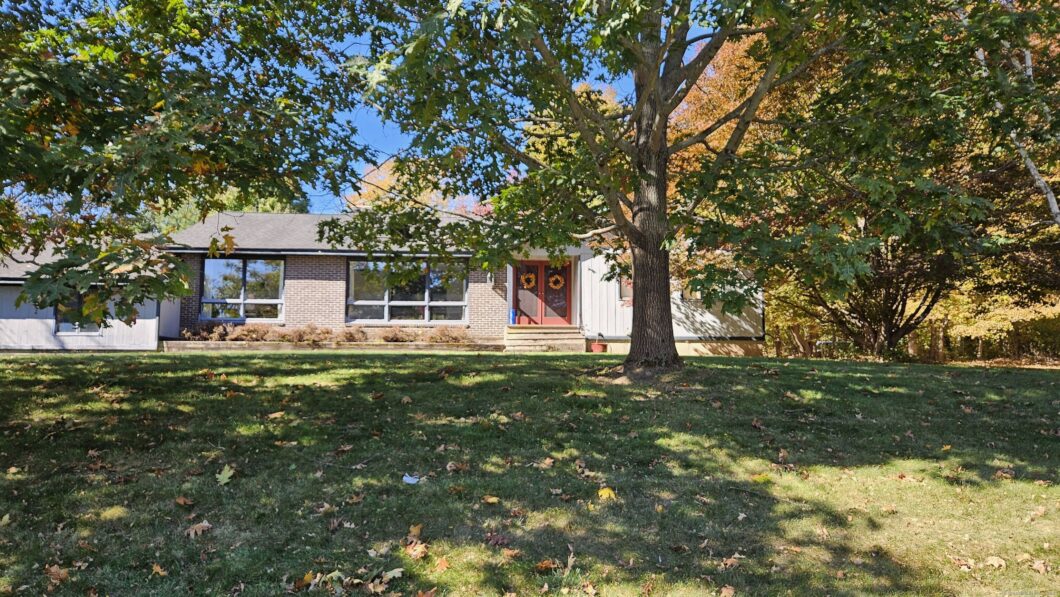 A cozy single-story house with a front yard and large tree.