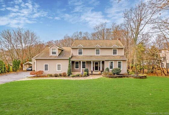 Large suburban home with beige siding and a spacious green lawn.